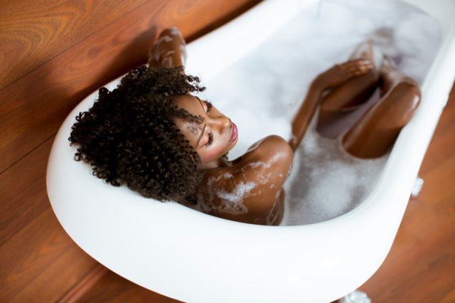 Beautiful african american woman bathing in a tub full of foam